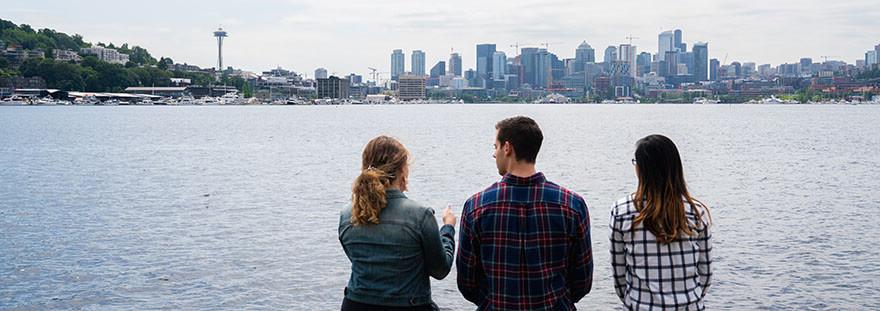 Three SPU students look out across Lake Union towards the 西雅图 skyline